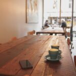 two gray ceramic mugs on brown wooden dining table